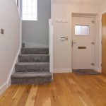 Modern hallway with wooden doors and grey carpet stairs