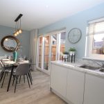 Modern dining area with glass table and pendant lights.