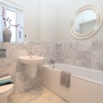 Modern bathroom with grey tiles and white fixtures.