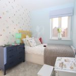Pastel-themed bedroom with butterfly wallpaper and blue dresser.