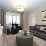 Modern living room with grey sofa, armchair, artwork.