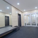 Modern apartment lobby with lift and glass doors.