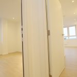 Bright empty apartment with wooden floors and large windows.