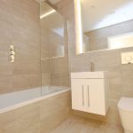 Modern bathroom with beige tiles and fixtures.
