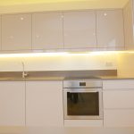 Modern kitchen with white cabinets and built-in oven.