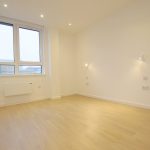 Empty room with wooden floor and large window.