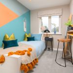 Modern bedroom with colourful decor and study area.
