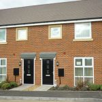 Modern semi-detached brick house with two doors.