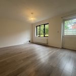Empty room with wooden floor and garden view.