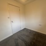 Small empty room with carpet and closed door.