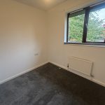 Small bedroom with carpet and window view.