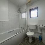 Modern bathroom with bathtub, toilet, sink, and window.