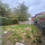 Residential garden with grass, trees, and wooden fences.