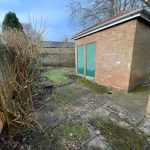 Garden area with shed and trimmed bushes.