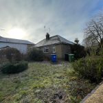 Suburban house with frosty garden and bins.
