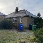 Brick bungalow with frosty garden and bins.