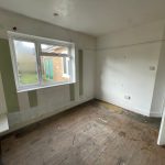 Empty room with striped walls and wooden floor.