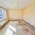 Empty room with stained floor and yellow walls.
