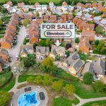 Aerial view of houses with "For Sale" sign.