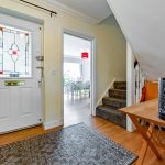 Bright hallway with stained glass door and staircase.