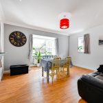 Bright living room with dining table and large clock.