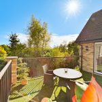 Sunlit garden with patio seating and trees.
