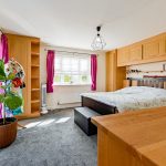 Bright bedroom with wooden furniture and large plant.