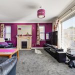 Spacious living room with purple accents and decor.