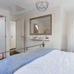 Modern bedroom with mirror and white decor.
