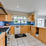 Modern kitchen with wooden cabinets and blue tiles.