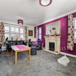 Modern living room with purple accents and fireplace.