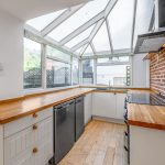 Modern kitchen with wooden countertops and brick wall.