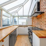 Sunlit kitchen with brick wall and wooden counters.