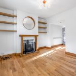 Minimalist living room with wooden floors and fireplace.