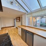 Spacious kitchen with wooden floor and garden view.