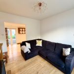 Modern living room with black sofa, wooden floor.