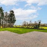 Sunny garden with trees and gravel patio.