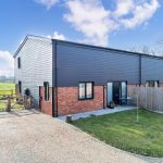 Modern countryside home with garden and blue sky.