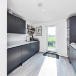 Modern kitchen with black cabinets and garden view.