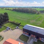 Aerial view of countryside house with large green field.
