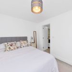 Minimalist bedroom with floral pillows and lamp.