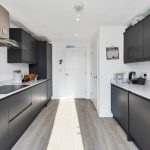 Modern kitchen with black cabinets and white countertops.