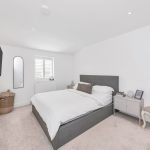Modern minimalist bedroom with grey bed and TV