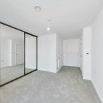 Empty room with mirrored sliding wardrobe doors.