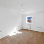 Empty room with window and beige carpet.