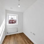 Small white room with wooden floor and window