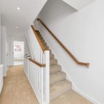 Carpeted staircase and hallway with wooden handrails.
