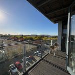 Sunny balcony overlooking cityscape and trees.
