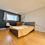 Minimalist bedroom with grey walls and wooden floor.