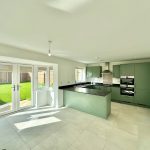 Modern kitchen with green cabinets and garden view.